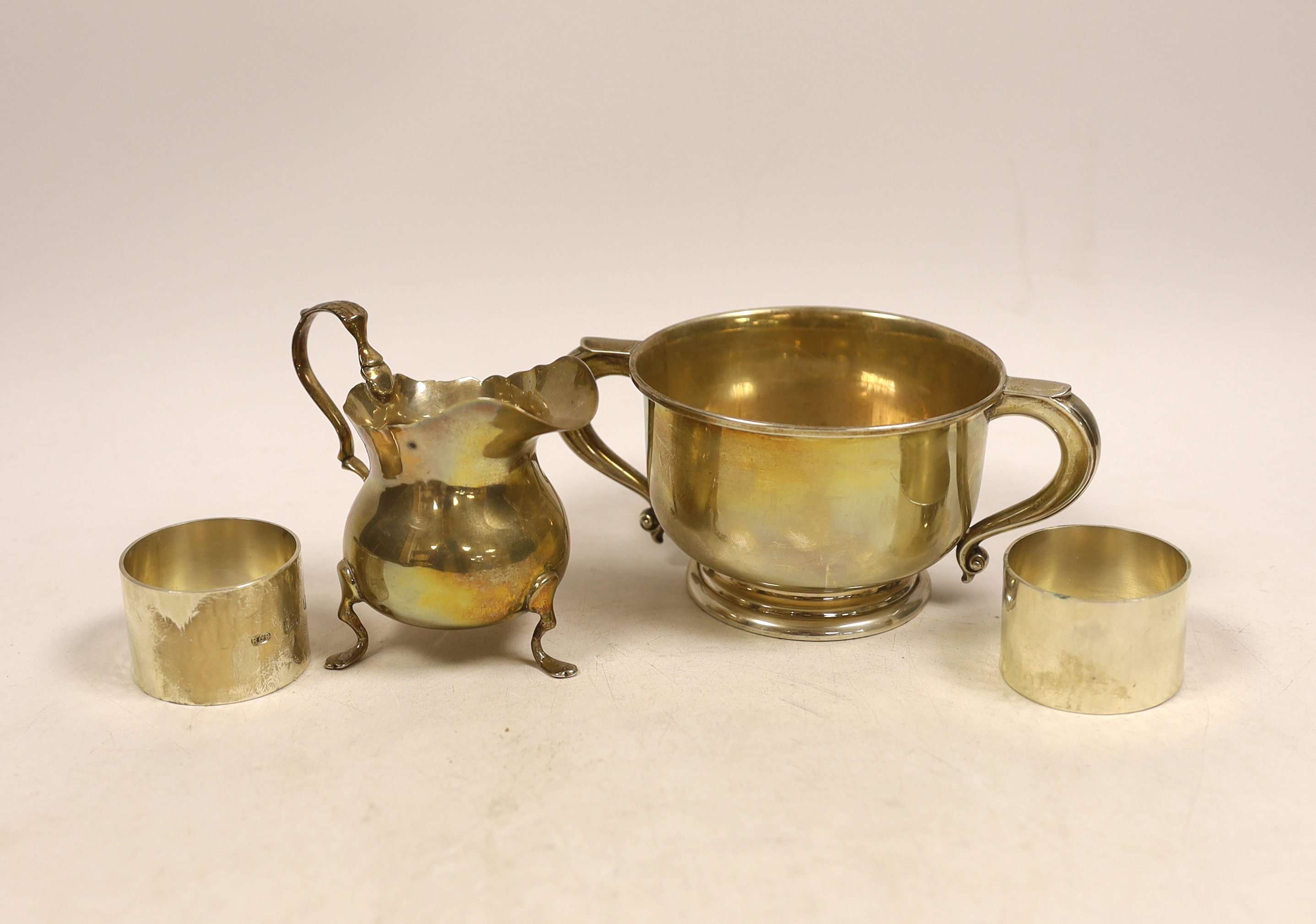 A silver bellied cream jug, a circular silver two handled bowl and a pair of modern silver napkin rings by Rodney Clive Petitt, 10.2oz.